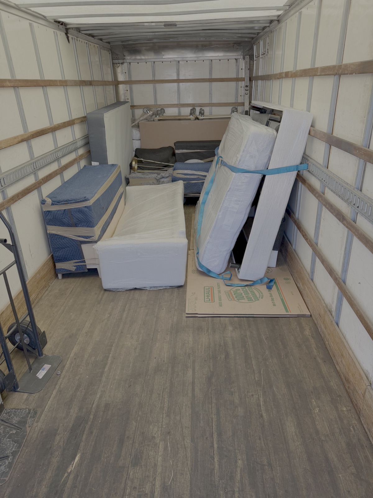 Wrapped furniture secured with straps inside a moving truck